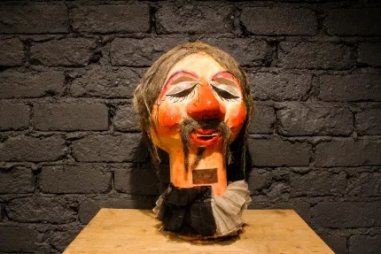Tête de carnaval papier mâché, couleurs vives et détails expressifs.