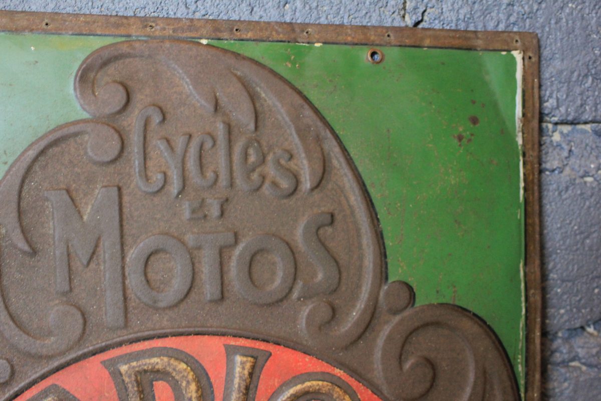 Tôle emboutie publicitaire vintage RADIOR aperçu du coin supérieur droit avec inscription de cycles et motos