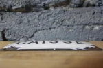 Gros plan sur l'inscription "CAISSE" de la plaque émaillée.